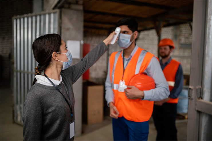 Checking body temperature of worker to ensure safety and health protocol